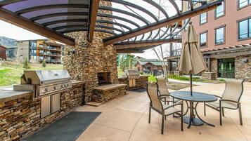 Une terrasse extérieure dotée d’une cheminée en pierre, d’un barbecue et d’un espace salon.