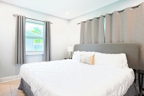 A hotel room with a bed, curtains, a window, and a nightstand.