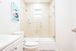 Een badkamer met een toilet, een badkuip en een douche.