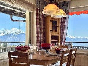 A dining table set with chairs, a red pot, wine glasses, and a view of snow-capped mountains. - Sunny Alpine Apartment - 180 View (Lens)
