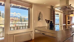 Een moderne keuken met een groot raam, uitzicht op bergen en een radiator.