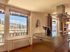 A modern kitchen with a large window, a view of mountains, and a radiator. - Sunny Alpine Apartment - 180 View (Lens)