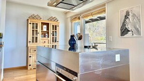 Een moderne keuken met een eiland van roestvrij staal, houten kastjes en een groot raam.