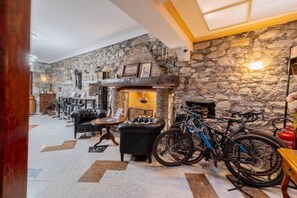 Eine Lobby mit Steinwänden, einem Kamin, Ledersitzmöbeln und Fahrrädern.