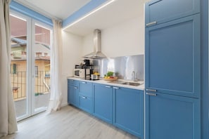 Eine moderne Küche mit blauen Schränken, einer Edelstahl-Dunstabzugshaube und einem Fenster mit Blick auf einen Balkon.