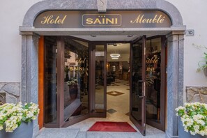 Ein Hotel mit einer Steinfassade, Glastüren und einem roten Teppich.