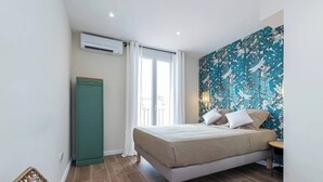 Een slaapkamer met een bed, een kledingkast, een raam met gordijnen en een muur met een bloemenmotief.