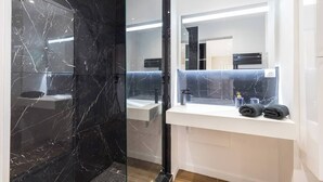 Een moderne badkamer met een douchecabine van glas, een wit wastafelmeubel en een grote spiegel.