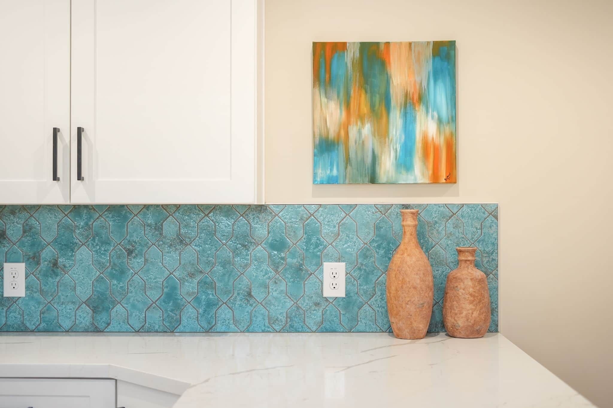 Een keuken met witte kasten, een blauw patroon op de achterwand en twee terracotta vazen op het aanrecht.