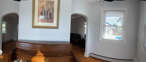 A hallway with wooden flooring, white walls, and multiple windows with blinds.