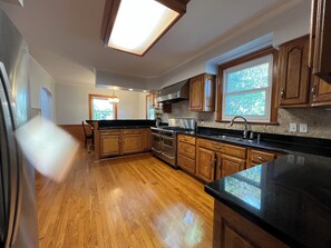 A kitchen with wooden cabinets, a black countertop, and a window. - Welcoming 3-bedroom house with AC in charming Norfolk (Norfolk)