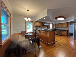 A spacious kitchen with wooden cabinetry, a central island, and a dining area with a bench. - Welcoming 3-bedroom house with AC in charming Norfolk (Norfolk)