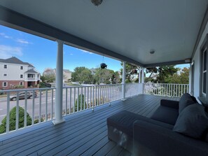 A covered porch with a sofa and a hanging plant. - Welcoming 3-bedroom house with AC in charming Norfolk (Norfolk)