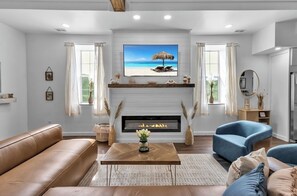 A living room with a fireplace, a television, and a sofa. - Luxury Barn Loft , Horses + Hot Tub (Cuba)