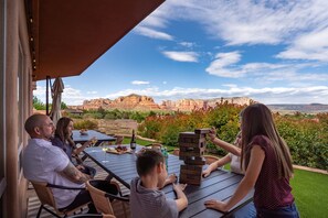 Eine Gruppe von Menschen spielt Jenga auf einer Terrasse im Freien mit einem malerischen Blick auf rote Felsformationen.