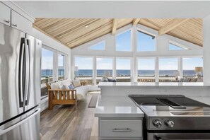 A modern kitchen with a large island, stainless steel appliances, and a view of the ocean. - Stunning Oceanfront Home with Private Beach! (Westerly)