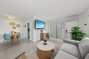 Ein modernes Wohnzimmer mit Essbereich, einem Flachbildfernseher und einer großen Pflanze.