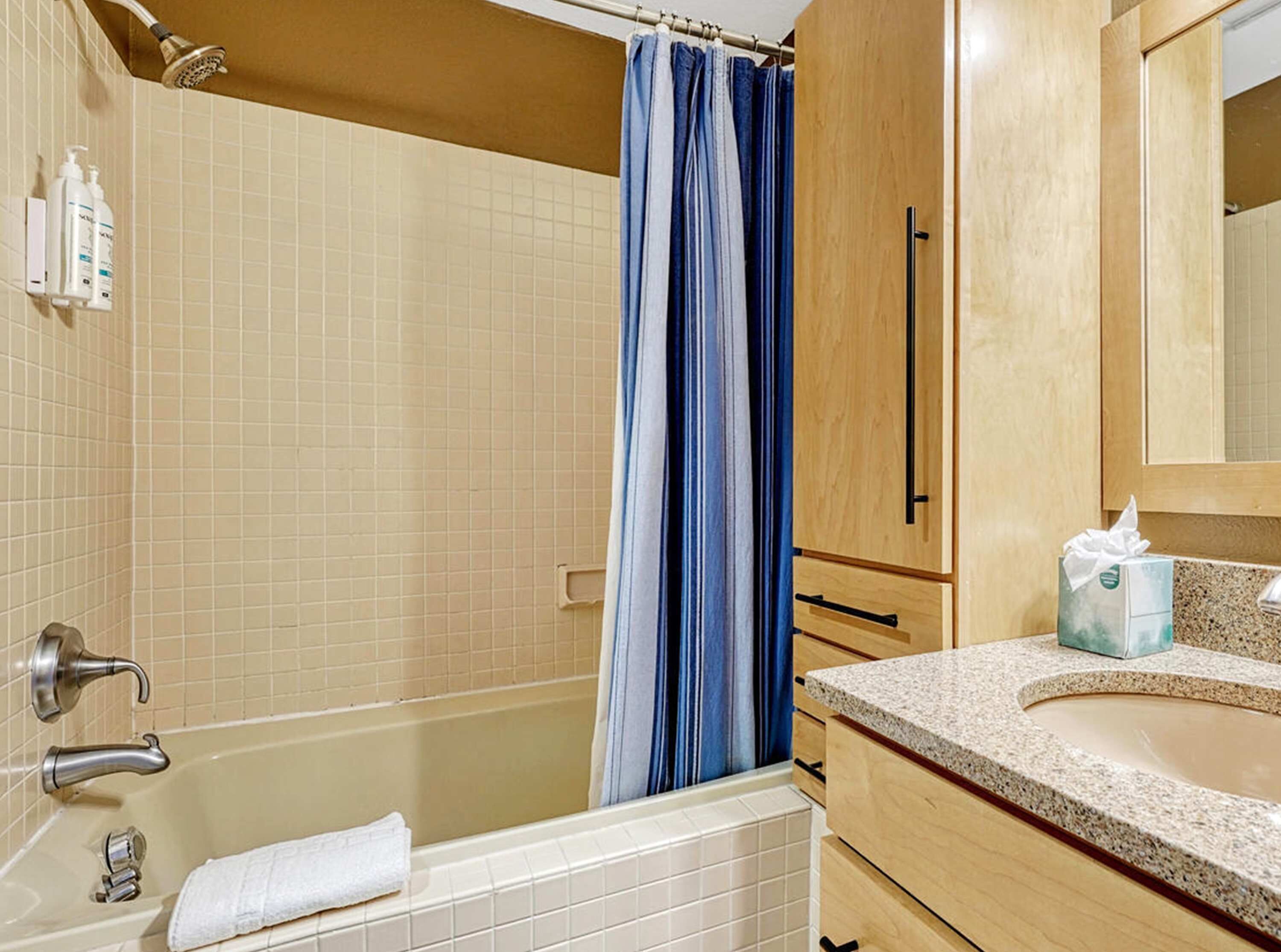 A bathroom with a bathtub, a shower, and a sink with a towel.