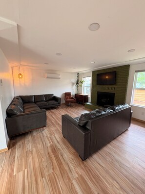 Ein modernes Wohnzimmer mit einer Eckcouch, einem Kamin und einem an einer Ziegelwand befestigten Fernseher.