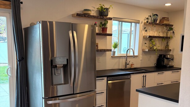 A modern kitchen with stainless steel appliances, wooden flooring, and built-in shelves with plants. - Cozy 2-bedroom house in tranquil Prescott Valley with AC (Prescott Valley)