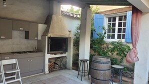 Eine Küche mit integriertem Grill, einem weißen Stuhl und einem Holzfass.
