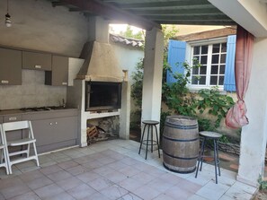 Eine Küche mit integriertem Grill, einem weißen Stuhl und einem Holzfass.