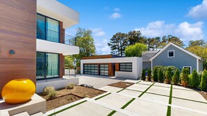 Ein modernes, zweistöckiges Haus mit Garage, einer gepflasterten Auffahrt mit Grasstreifen und einem großen, gelben Zierteil.