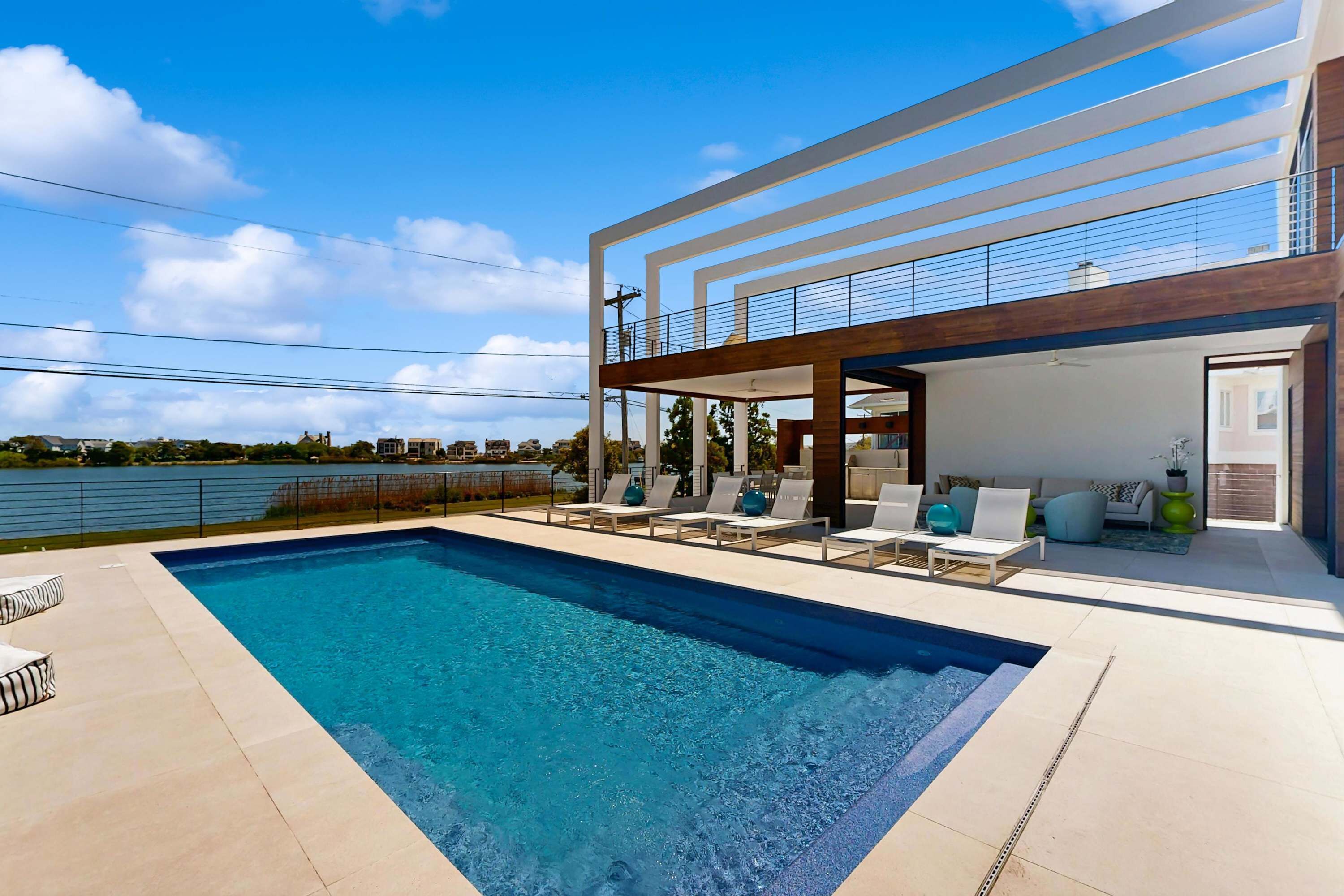 Ett modernt hus med en swimmingpool, en uteplats och utsikt över vattnet.