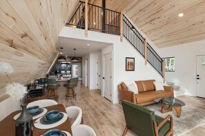 A spacious loft-style living area with a kitchen, dining table, and a staircase leading to an upper level.