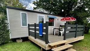 Ein Wohnmobil mit einer Veranda, einem Tisch und Stühlen sowie einem roten Sonnenschirm.