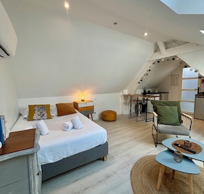 Een slaapkamer met een bed, nachtkastje en een klein bureau met stoel.