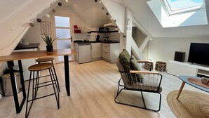 Eine Loft-Wohnung mit Küche, Essbereich und Wohnraum, ausgestattet mit einem Oberlicht und freiliegenden Holzbalken.