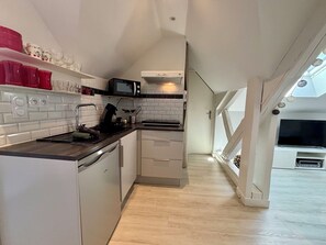 Een moderne keuken met witte kastjes, een zwart aanrecht en een magnetron.