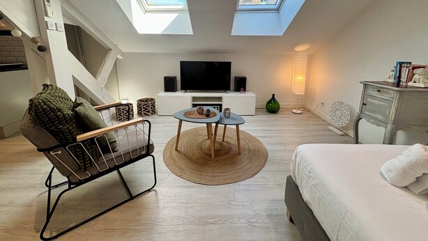 Eine moderne Lofts-Wohnung mit Dachfenstern, einem Fernseher, einer Couch und einem Essbereich.