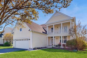 Ein zweistöckiges Haus mit Veranda, Garage und einem gepflegten Rasen.