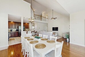 A spacious dining area with a white table, white chairs, and woven placemats. - Swann Cove spacious house with community pool (Selbyville)