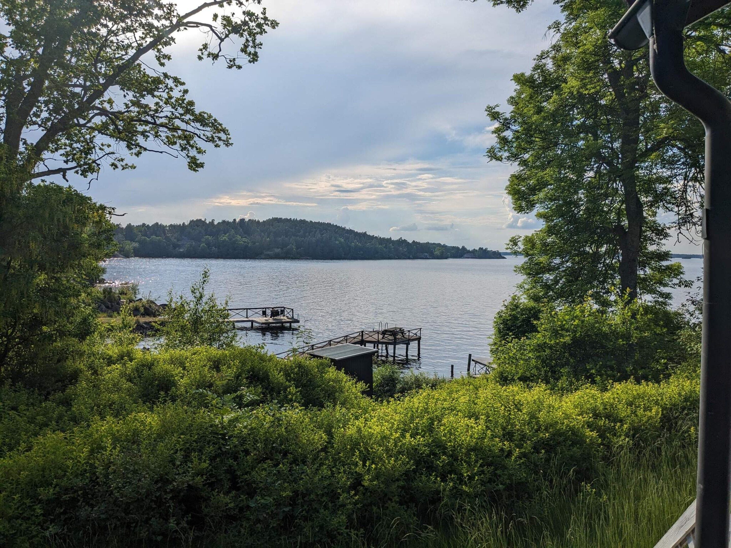 A lake with a dock and a small boat, surrounded by dense greenery and trees.
