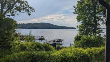 A lake with a dock and a small boat, surrounded by dense greenery and trees.