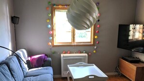 A living room with a sofa, a table, a TV, and a window with a view. - 4 Star Holiday Home in Eskilstuna (ESKILSTUNA)