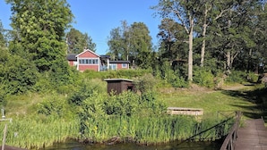 A wooden dock extending over a calm body of water, surrounded by lush greenery and a small wooden structure. - 4 Star Holiday Home in Eskilstuna (ESKILSTUNA)