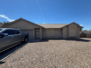 A residential house with a gravel driveway, a parked truck, and a satellite dish.