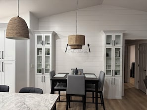 Una cocina moderna con armarios blancos, encimera de mármol y una lámpara colgante de fibras.