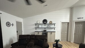 Ein Wohnzimmer mit einer Couch, einem kleinen Tisch und einer Küchenzeile mit Regalen.