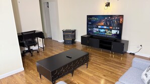 Ein Wohnzimmer mit Fernseher, Sofa, Couchtisch, TV-Schrank und Kamin.
