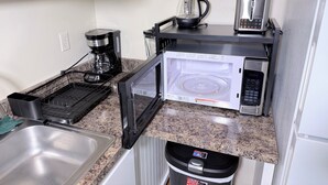 Eine Küche mit Mikrowelle, Kaffeemaschine und Wasserkocher auf der Arbeitsfläche.