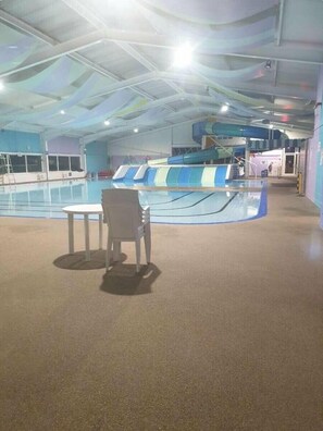 Ein Innenpool mit Rutsche, ein kleiner Tisch mit Stühlen und eine Decke mit einzigartigem Design.