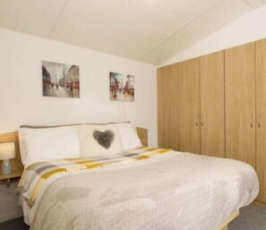 Ein Schlafzimmer mit einem Bett, einem Holzschrank und zwei an der Wand hängenden Bildern.