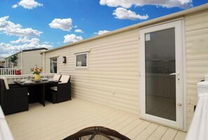 Ein Wohnmobil mit einer Terrassenfläche, komplett mit Tisch und Stühlen, einer Schiebetür und einem kleinen Fenster.