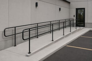 A set of concrete steps with a metal handrail, a door, and a parking area with a yellow line.