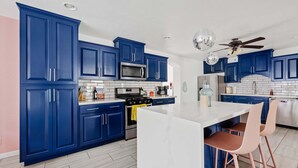 Eine moderne Küche mit blauen Schränken, einer weißen Kochinsel und einem Deckenventilator.